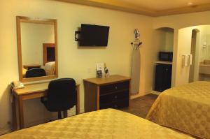 a hotel room with a bed and a desk and a mirror at Maverick Inn in Eagle Pass