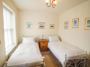 two beds in a room with two windows at Alpen Rose Cottage in Portland