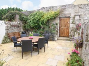 een patio met een houten tafel en stoelen voor een gebouw bij Alpen Rose Cottage in Portland