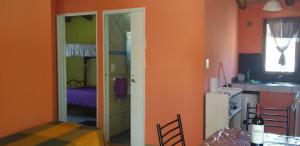 a room with orange walls and a kitchen with a door at La Nave del Olvido- Cabaña Potrerillos in Potrerillos
