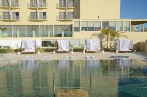 a swimming pool with chairs and a building at E-Hotel Larnaca Resort & Spa in Larnaka
