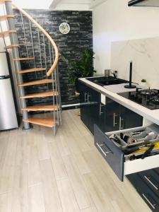 a kitchen with a staircase and a counter with a sink at Au cœur des montagnes in Capesterre-Belle-Eau