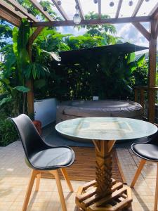 a patio with a table and chairs and a pergola at Au cœur des montagnes in Capesterre-Belle-Eau