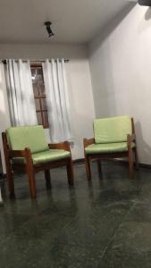 two green chairs sitting in a room with a window at Pousada da Jaqueira - EPP in Rio das Ostras