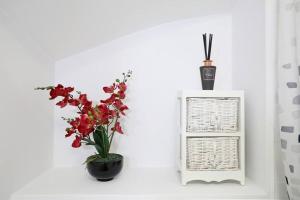 a vase of red flowers sitting next to a cabinet at Stafford Rest Ginger & Gold Ltd in Norwich