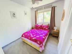 a bedroom with a bed with pink sheets and a window at KIANI HOME in Afaahiti