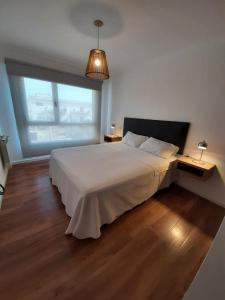 een slaapkamer met een wit bed en een groot raam bij Departamentos DSM in Necochea