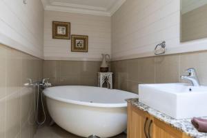 a bathroom with a large white tub and a sink at Stonelinks House sleeping 12 in Leura