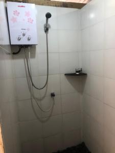 a shower with a hose in a white tiled bathroom at Chakra Tavern in Bedugul +43 photos