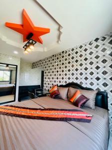 a bedroom with a large bed with a star on the wall at โรงแรมเรือนคุณเล็ก กานต์สินี in Ban Tha Pho