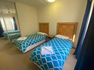 a bedroom with two beds and a mirror at Unit 46 Seafront Estate in Jurien Bay +9 photos