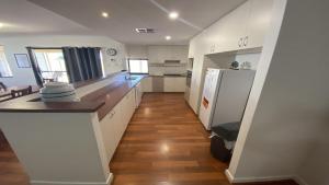 a kitchen with white cabinets and a wooden floor at Maniki Gardens in Jurien Bay