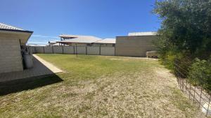 a backyard with a fence and a grass yard at Maniki Gardens in Jurien Bay