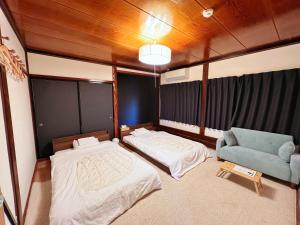 1 dormitorio con 2 camas y silla azul en Shirakawago Guest House Kei en Shirakawa