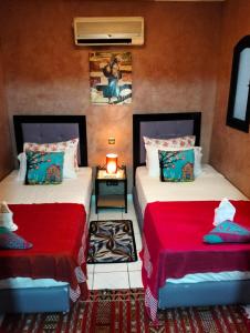 马拉喀什Riad Lounge à Marrakech的一间卧室配有两张红色床单