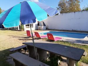 a picnic table with an umbrella next to a swimming pool at BenjaCha in Cerrillos