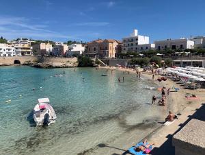 a beach with people and a boat in the water at Dimora del Casale in Brindisi