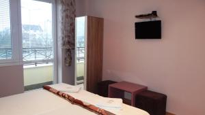 a room with a bed and a tv and a window at Guest Rooms Kom in Sofia
