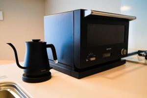 那覇市にあるBranchera Naha 1402の電子レンジの横のカウンターに設置された黒いコーヒーメーカー
