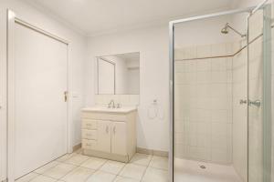 a white bathroom with a shower and a sink at Views on Bayview in Cowes +10 photos