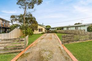 a home with a fence and a dirt road at Views on Bayview in Cowes
