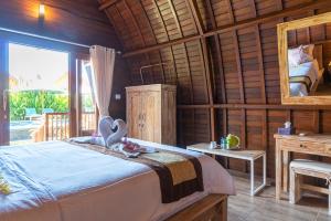 1 dormitorio con cama, escritorio y espejo en Kukuh Penida Village en Nusa Penida