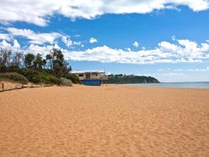 a sandy beach with a house in the background at Designer Luxury for 2 in Mornington