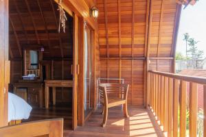 une terrasse couverte en bois avec une chaise et un bureau dans l'établissement Kukuh Penida Village, à Nusa Penida