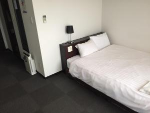 a hotel room with a bed and a lamp on a table at Omura Station Hotel in Omura