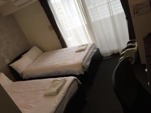 two beds in a small room with a window at Omura Station Hotel in Omura +2 photos