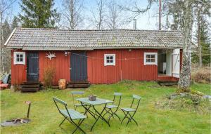 een rode schuur met stoelen en een tafel ervoor bij Awesome Home In Hallstavik With Wifi in Hallstavik