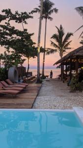 una piscina junto a una playa con palmeras en Happiness Beach Resort Siargao, en General Luna