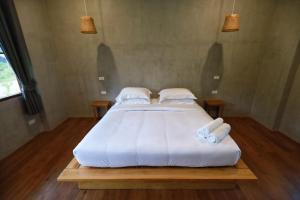 een groot wit bed in een kamer met 2 kussens bij The Liveliwoods in Khao Sok