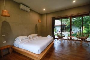 a bedroom with a large bed and a patio at The Liveliwoods in Khao Sok