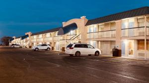 two cars parked in a parking lot in front of a building at Days Inn by Wyndham Salina South in Salina