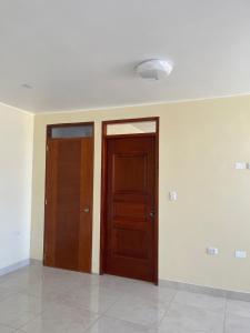 two wooden doors in a room with white walls at Casa Galarza in Huancayo