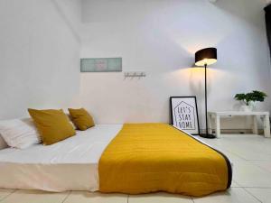 um quarto com uma cama grande e um cobertor amarelo em The_Mozy Homestay em Tanjong Sepat