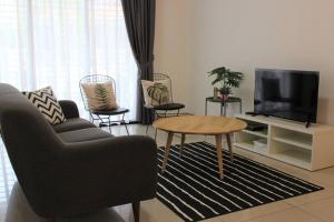 a living room with a couch and a tv and a table at The_Mozy Homestay in Tanjong Sepat