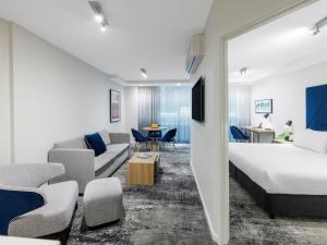 a bedroom with a bed and a living room at Brady Apartment Hotel Flinders Street in Melbourne