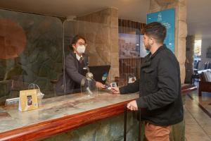 Een man met een masker aan een toonbank. bij Casa Andina Premium Puno in Puno