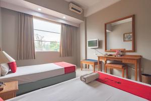 um quarto com 2 camas, uma secretária e um espelho. em RedDoorz near Institut Teknologi Bandung 2 em Bandung