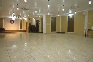 een grote kamer met een grote tegelvloer en verlichting bij Hotel Maa International in Alīpur Duār