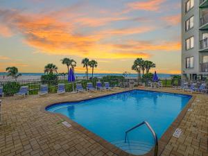 a swimming pool with chairs and a building and the ocean at Caprice 401 in St. Pete Beach