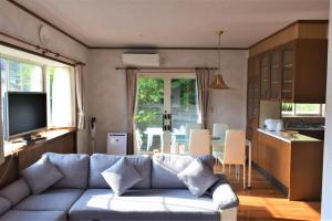 a living room with a couch and a kitchen at ritomaru house iki ashibe in Iki