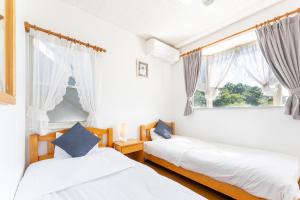 two beds in a room with a window at Tabist Kiyosato Grandeur Yatsugatake in Hokuto