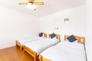 three beds in a room with a ceiling fan at Tabist Kiyosato Grandeur Yatsugatake in Hokuto