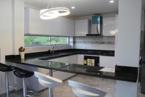 una cucina con bancone nero e armadietti bianchi di Nueva, Moderna casa en Silvania con Jacuzzi a Silvania