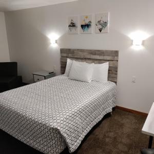 1 dormitorio con 1 cama con sábanas blancas y 2 luces en High Desert Inn, en Salina
