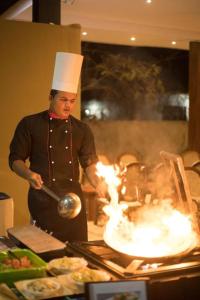 Ein Mann in einem Kochhut, der in einer Küche kocht. in der Unterkunft Camellia Resort and Spa in Sigiriya