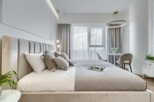 een witte slaapkamer met een groot bed en een tafel bij Apartament Ariela LUX 17th fl HANZA in Szczecin